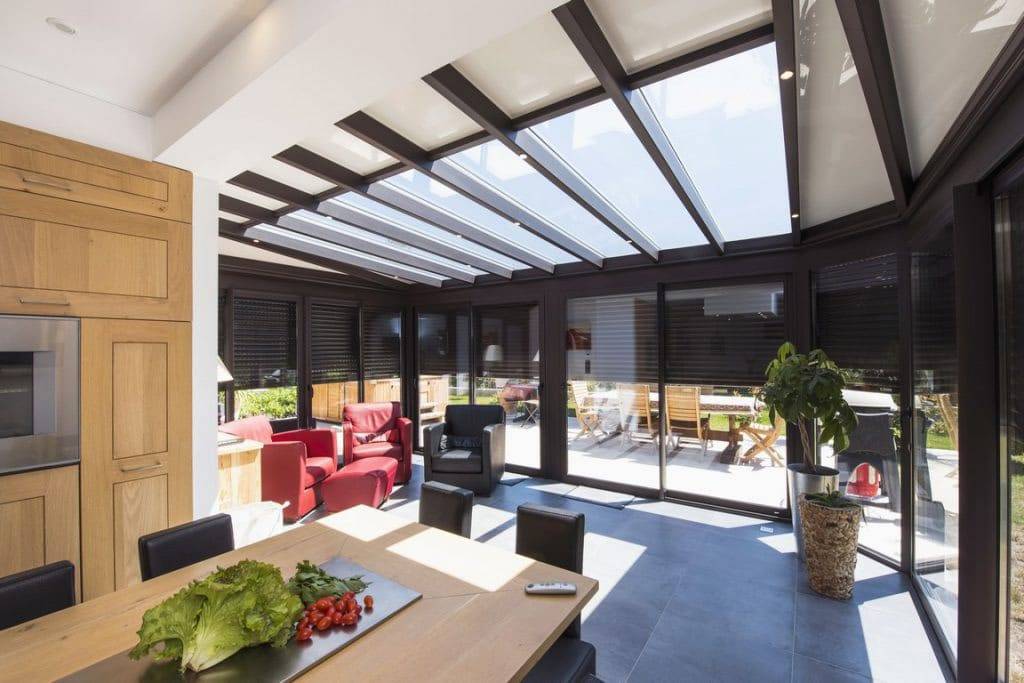 Véranda lumineuse moderne avec toit transparent et espace détente