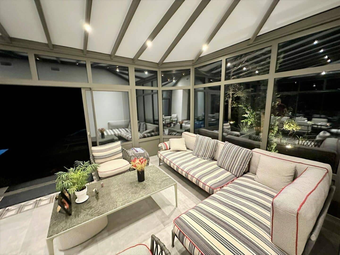 Véranda moderne avec mobilier confortable et vue jardin éclairée