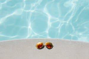 im2 Lunettes de soleil posées au bord d'une piscine bleue.
