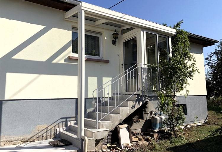 Véranda d'entrée attachée à une maison à étage avec des escaliers