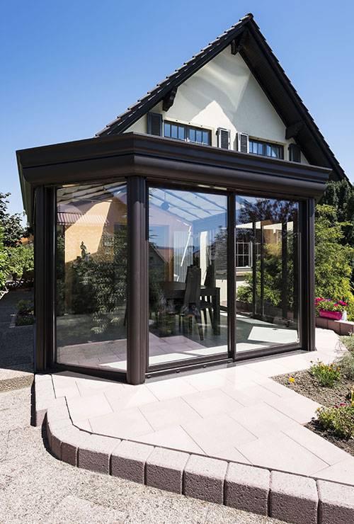 Véranda moderne en verre et métal adossée à une maison
