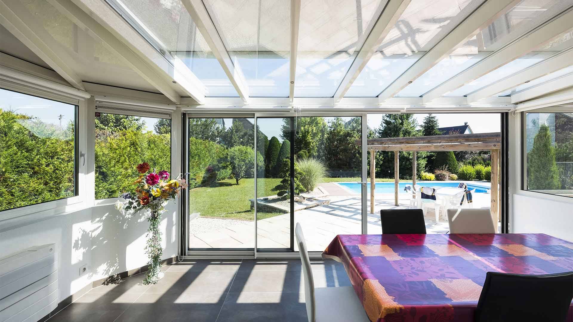 Véranda lumineuse avec vue sur jardin et piscine