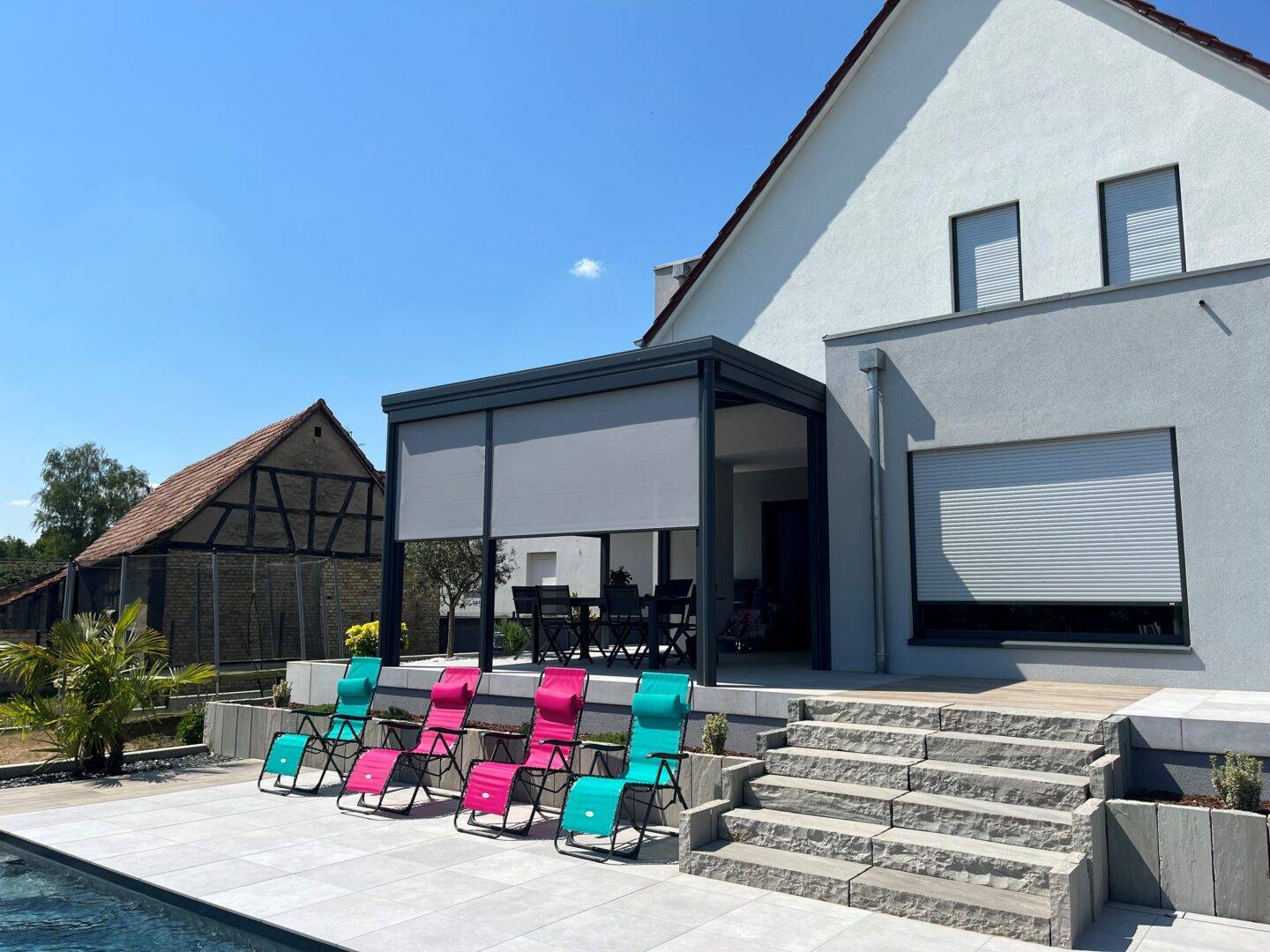 Pergola moderne avec chaises colorées à côté d'une piscine