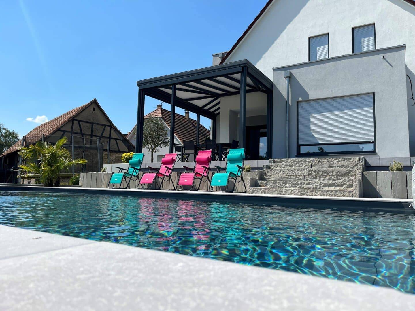 Véranda moderne avec vue sur piscine et chaises colorées