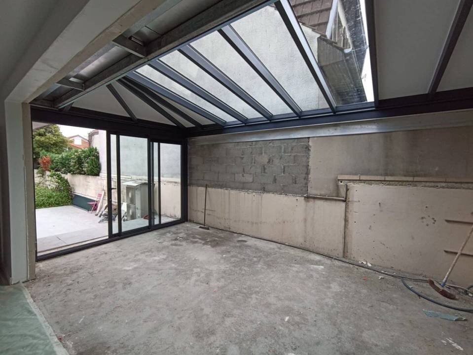 1698238512582 Véranda moderne en construction avec vue sur le jardin verdoyant