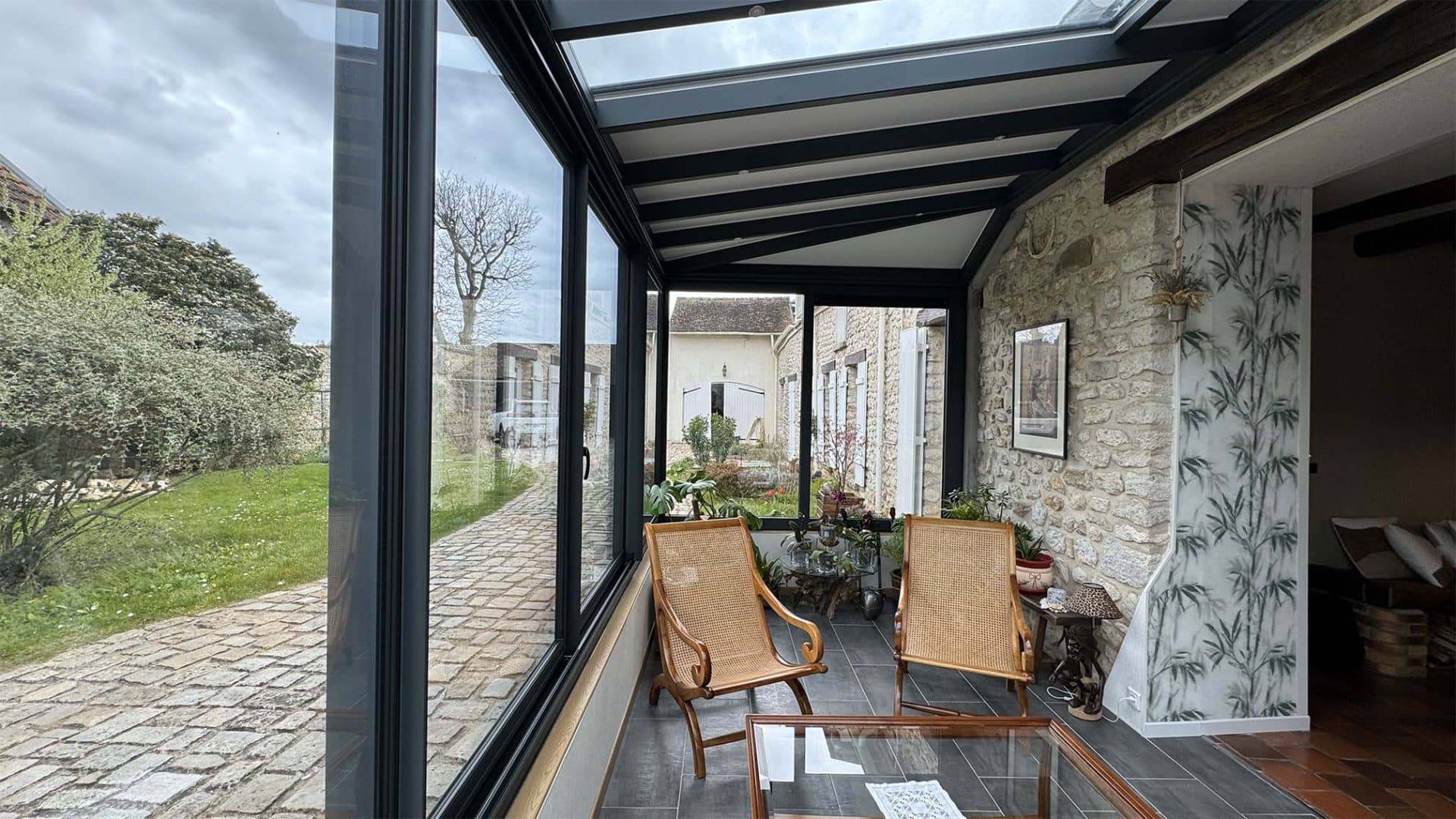 Véranda moderne avec grandes baies vitrées et espace détente lumineux