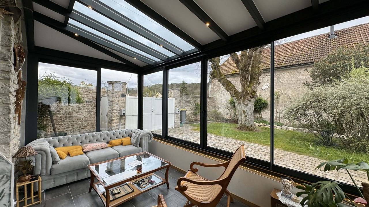 Petite véranda salon sur muret Véranda moderne avec structure vitrée et coin salon confortable