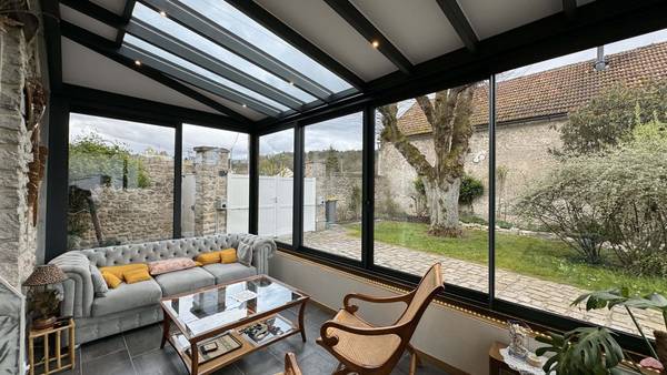 Petite véranda salon sur muret Véranda moderne avec structure vitrée et coin salon confortable