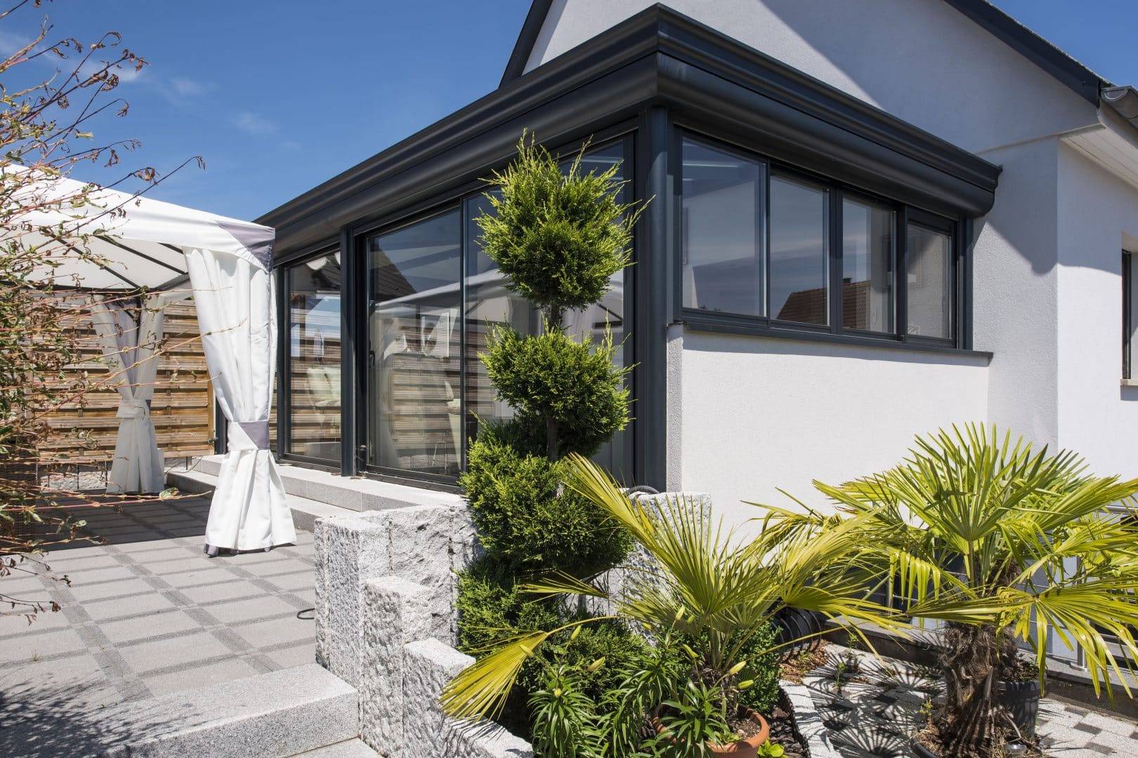 Véranda moderne avec baies vitrées adjacente à un jardin aménagé