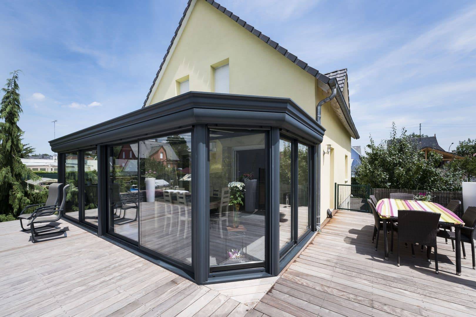 Véranda moderne en aluminium avec terrasse en bois accueillante