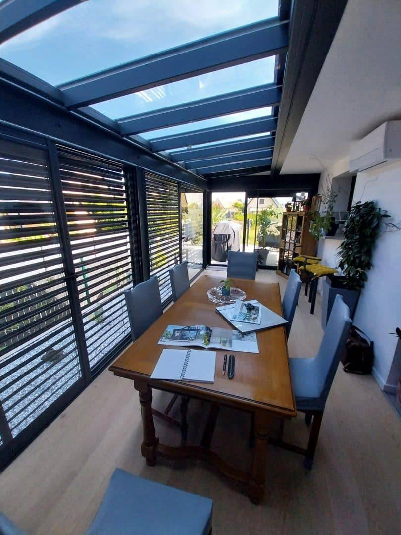 Véranda moderne avec toit en verre et stores intégrés
