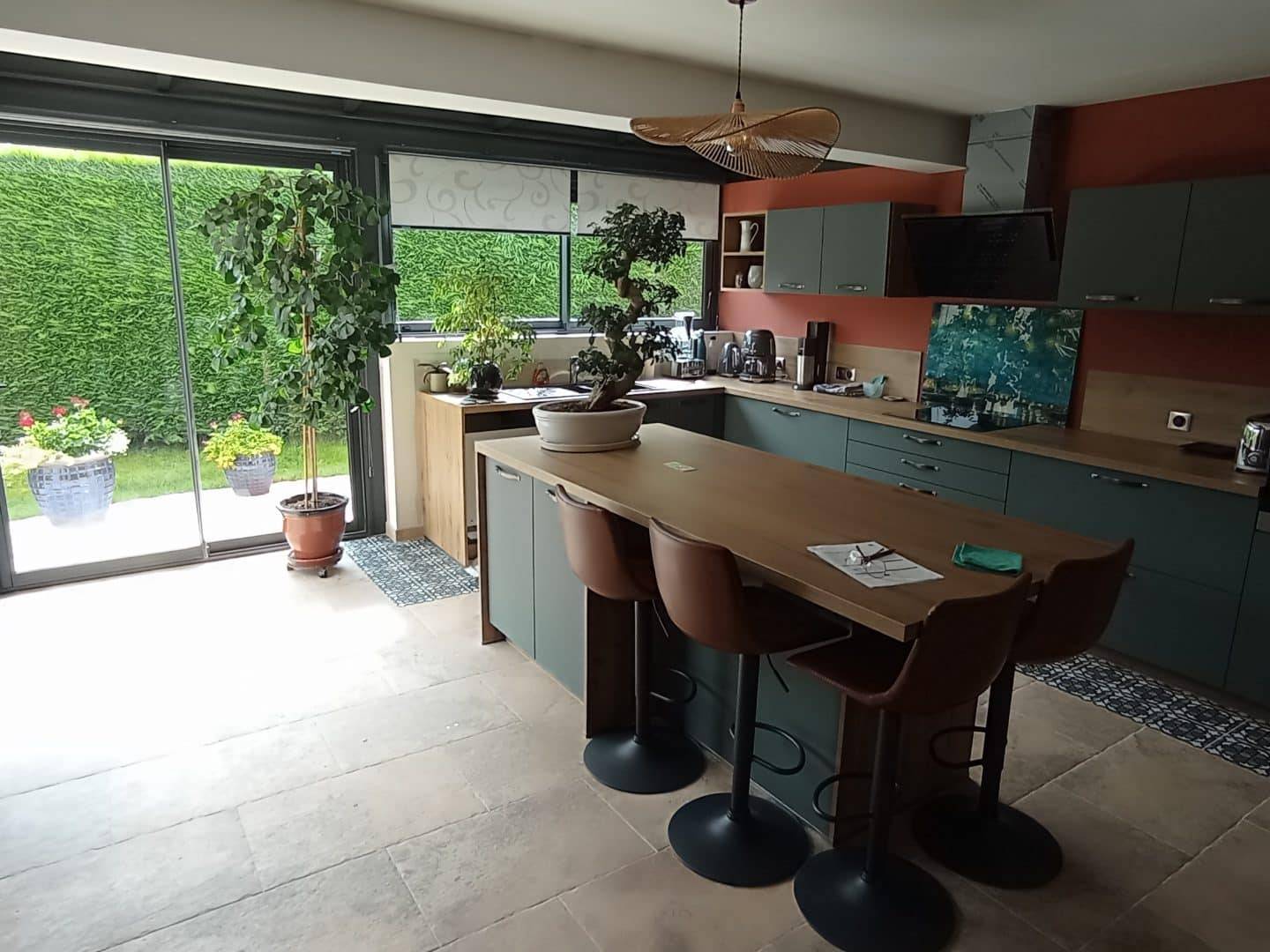 Cuisine ouverte donnant sur une véranda lumineuse avec grande baie vitrée