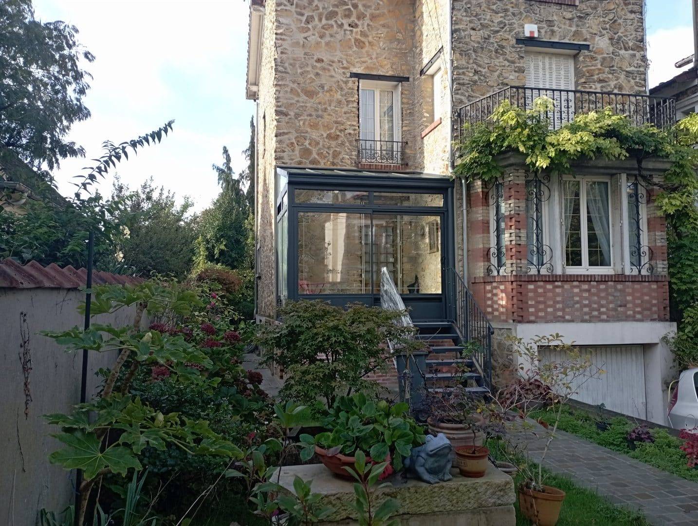 Véranda sas d'entrée intégrée dans une maison en pierre rustique