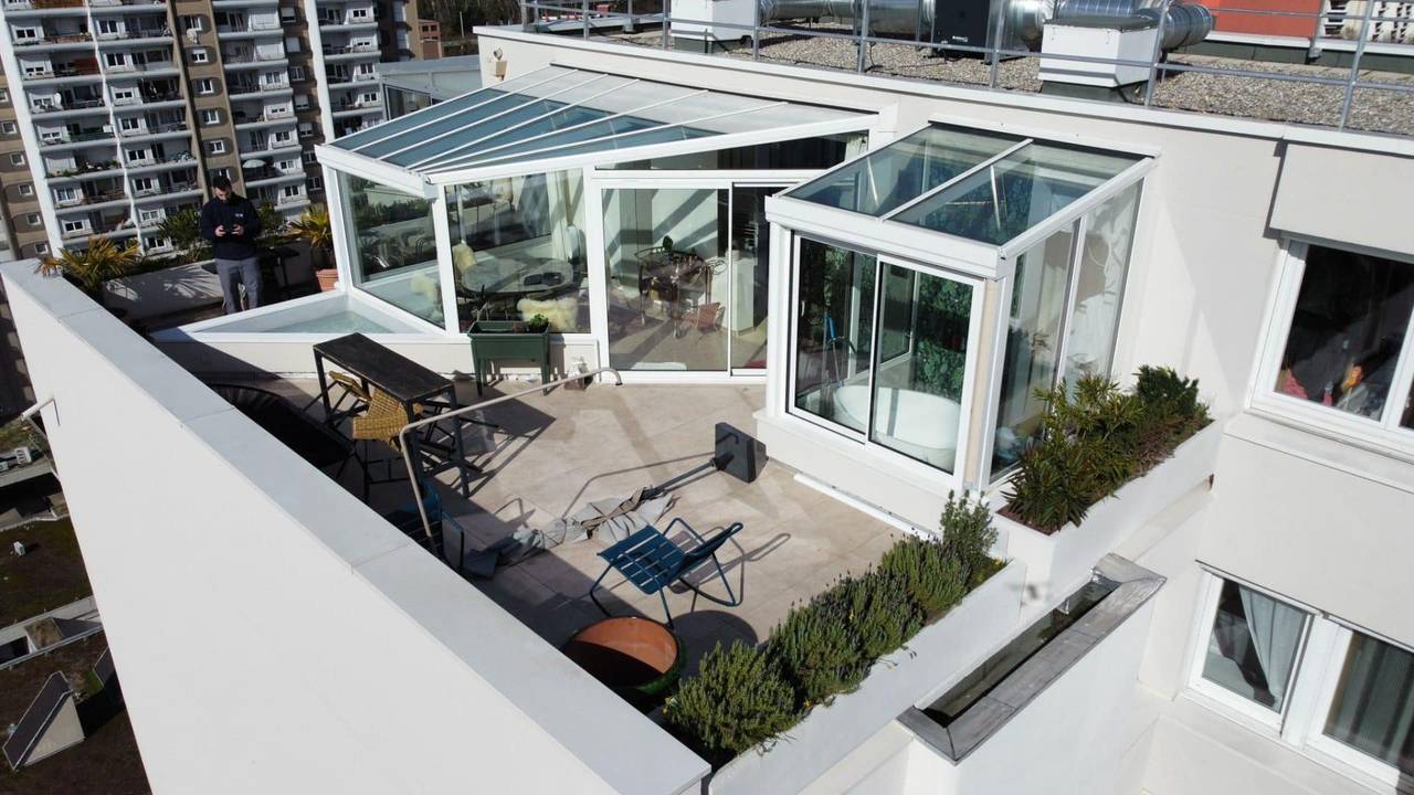 Véranda sur toit terrasse Élégante véranda vitrée moderne sur toit-terrasse en milieu urbain