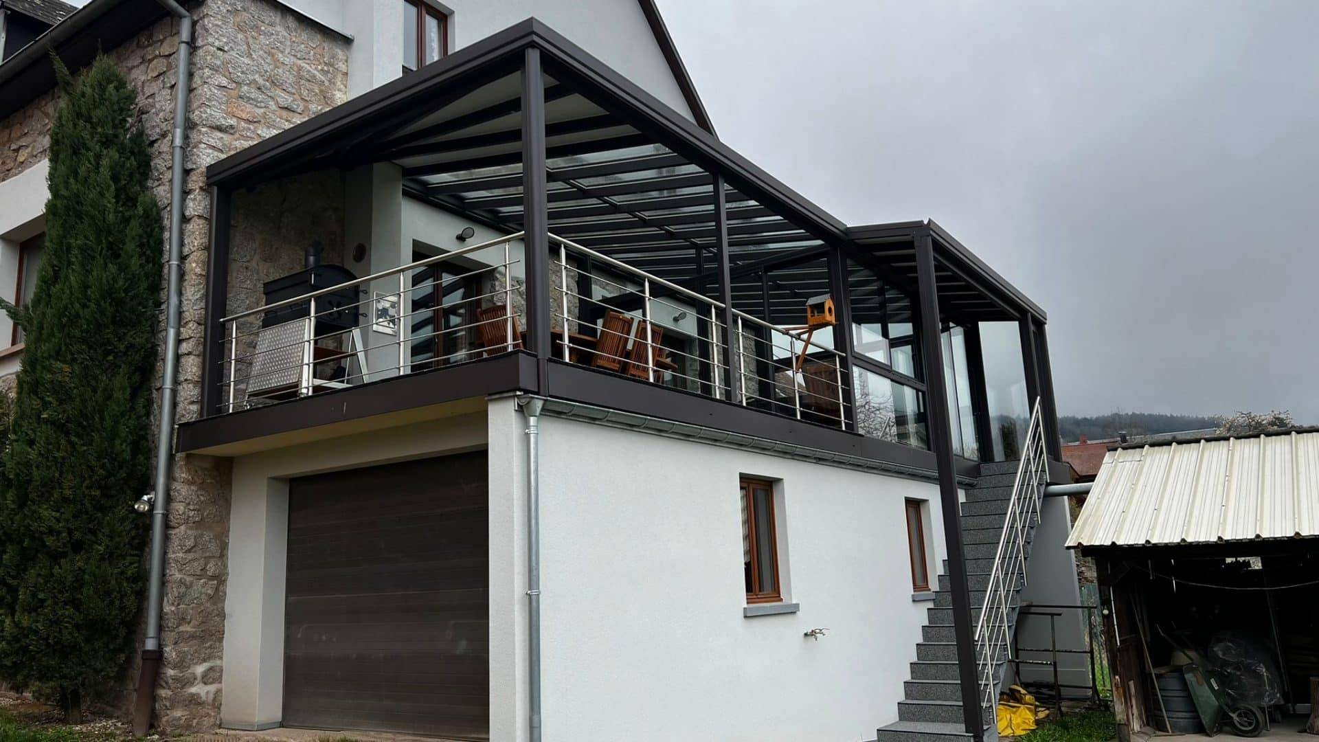 Véranda élégante en aluminium et verre accrochée à une maison