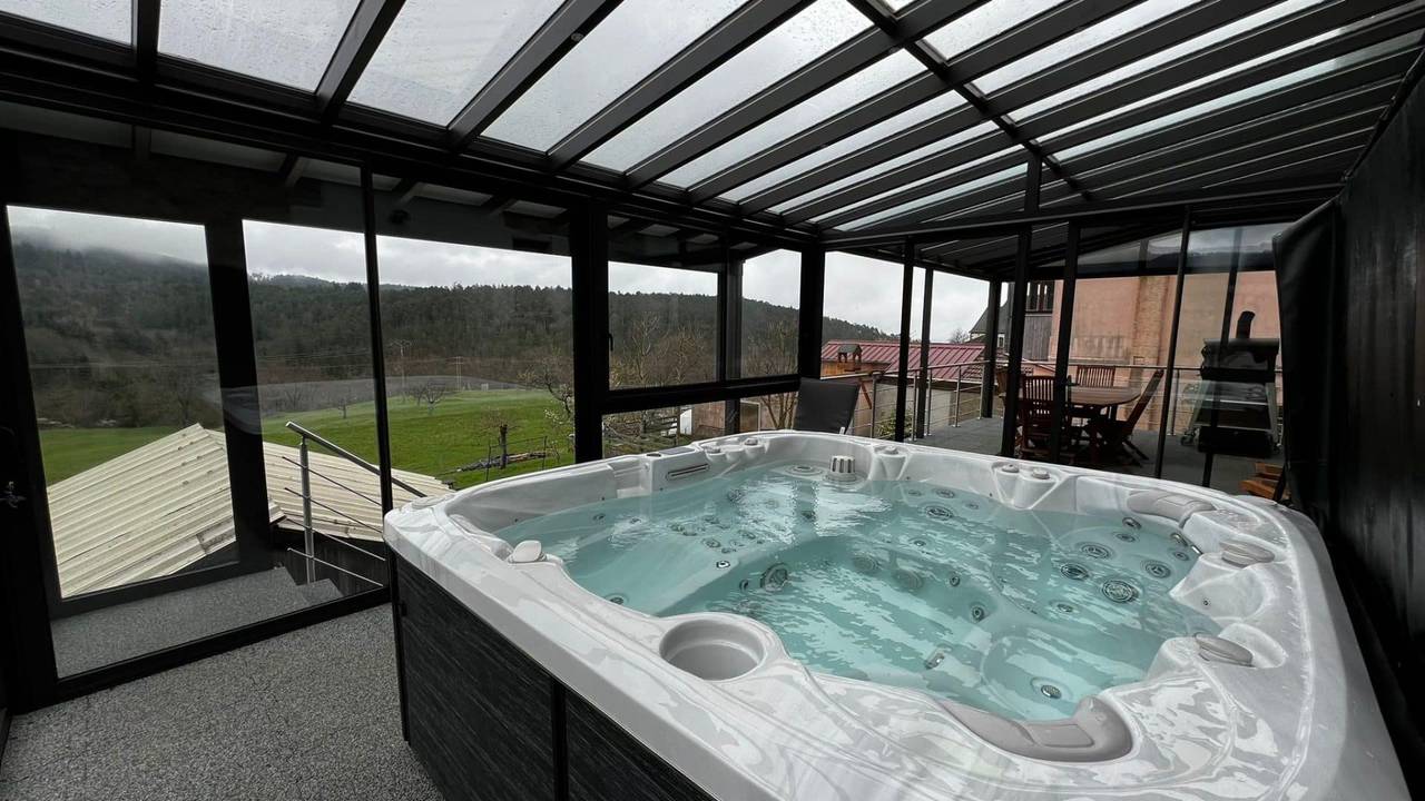 Pergola et véranda sur terrasse Véranda moderne avec spa intégré offrant une vue panoramique