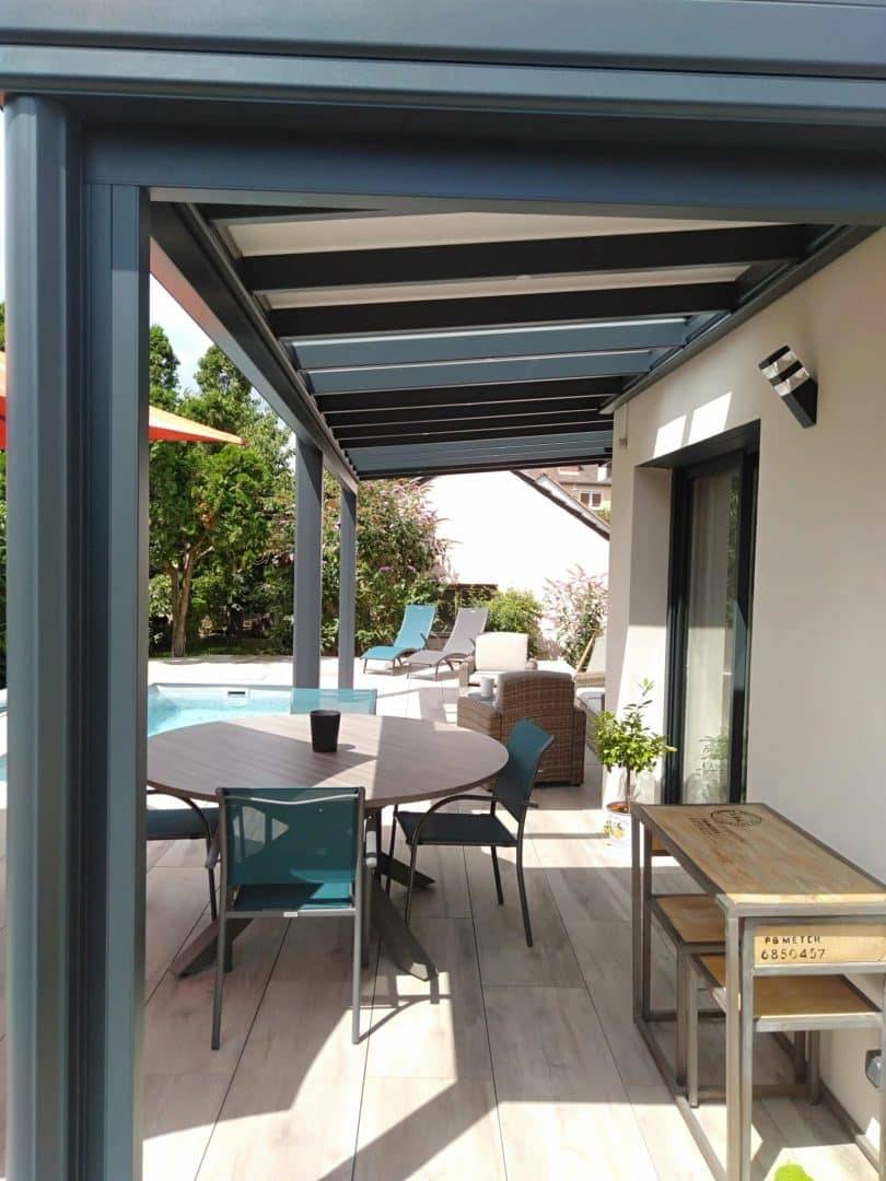 Pergola moderne aménagée avec mobilier extérieur près d'une piscine