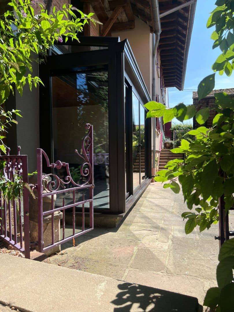 Véranda moderne en verre et aluminium dans un jardin accueillant