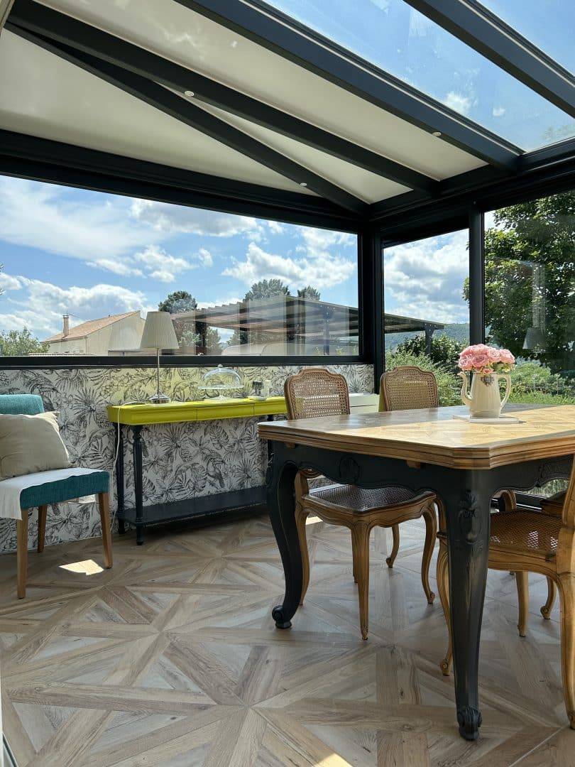 Véranda lumineuse avec toit en verre et mobilier élégant