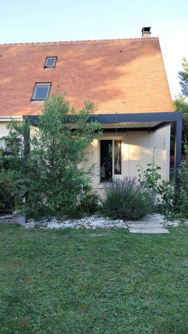 Pergola moderne adossée à une maison avec jardin verdoyant