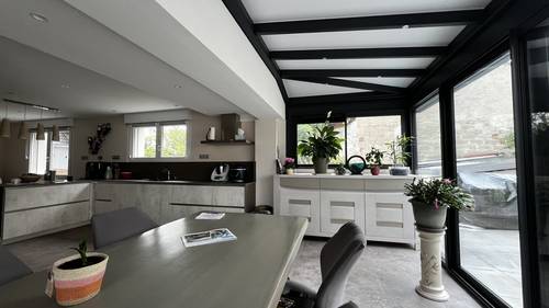 Véranda extension cuisine Véranda moderne avec plantes vertes et mobilier contemporain