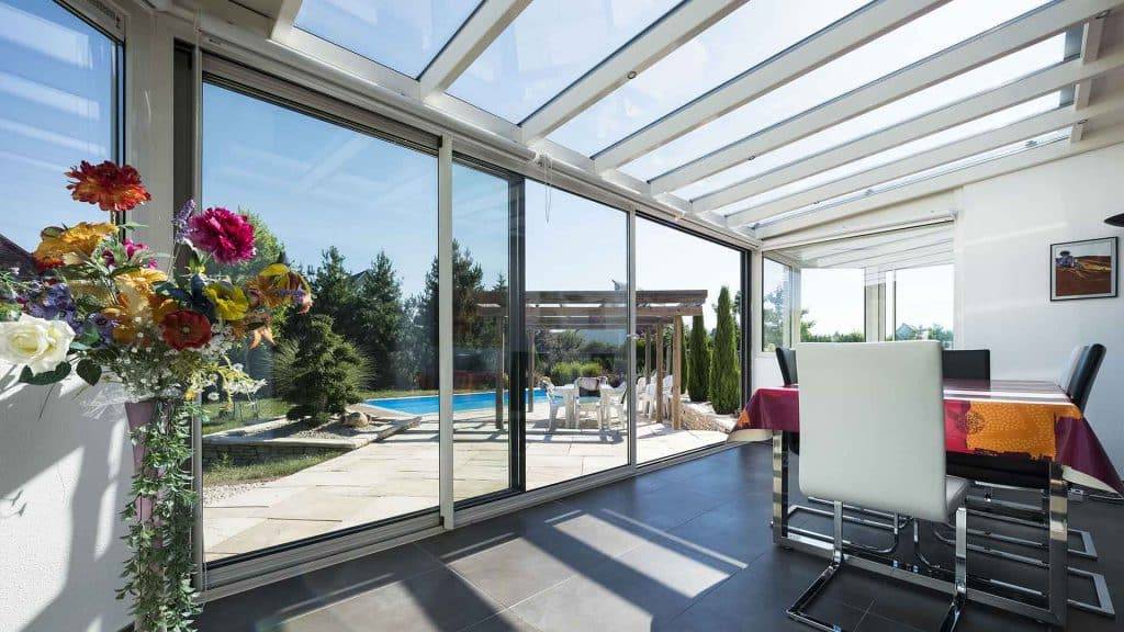 Véranda moderne avec vue sur piscine et jardin fleuri