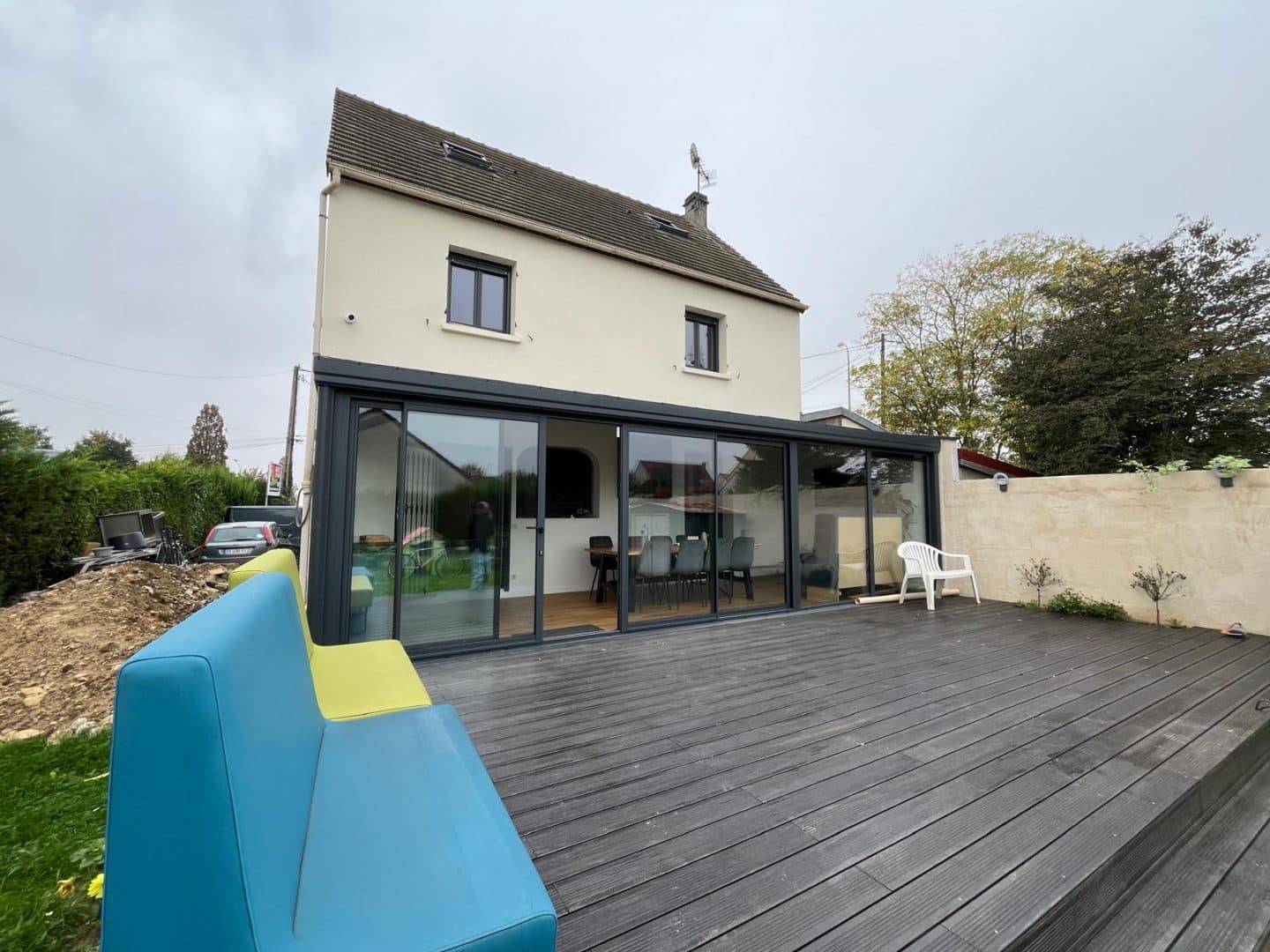 Véranda moderne en verre avec terrasse en bois accueillante