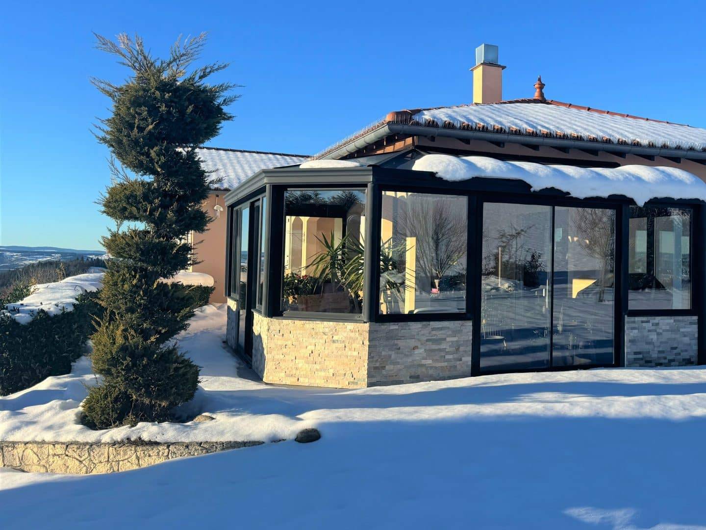 Véranda moderne vitrée dans un jardin enneigé ensoleillé