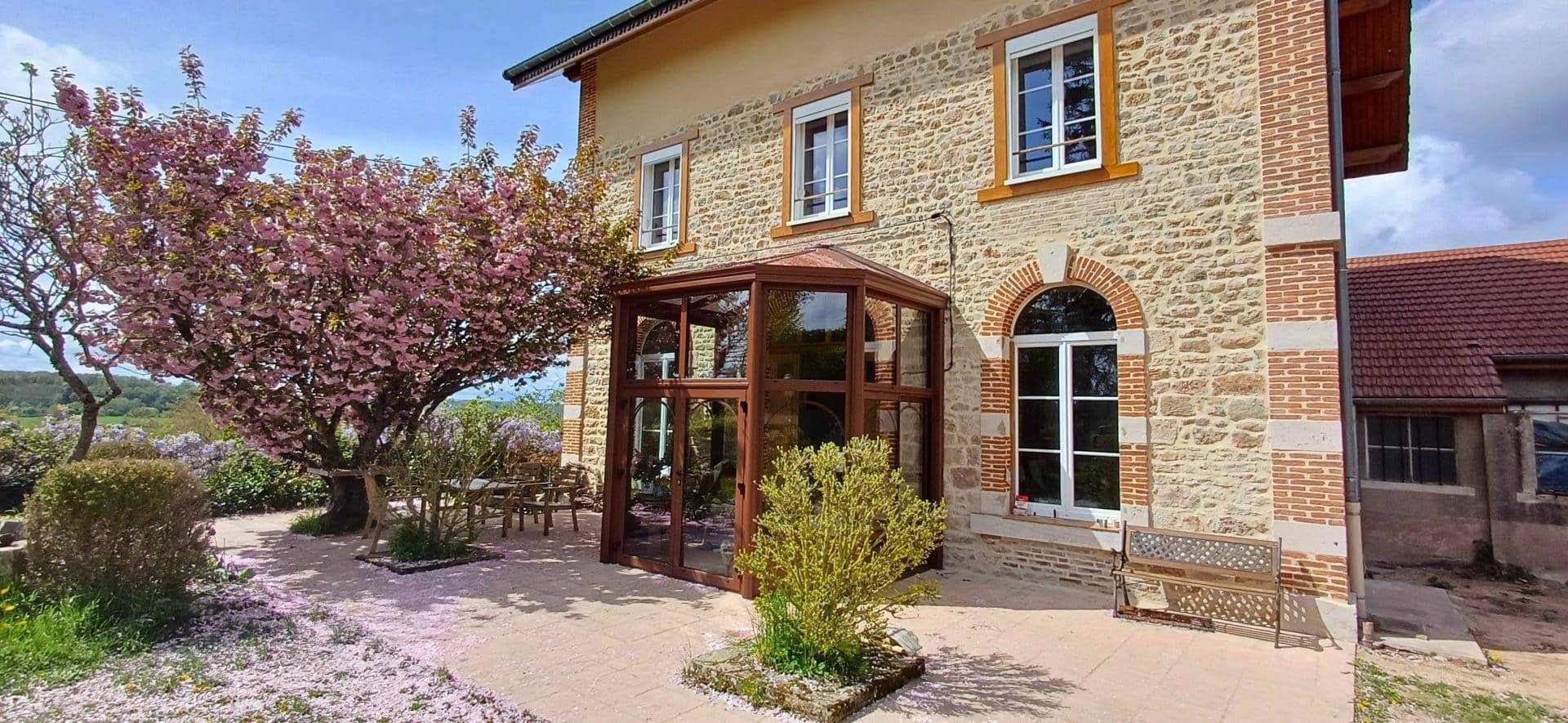 Véranda ensoleillée adossée à une maison en pierre élégante