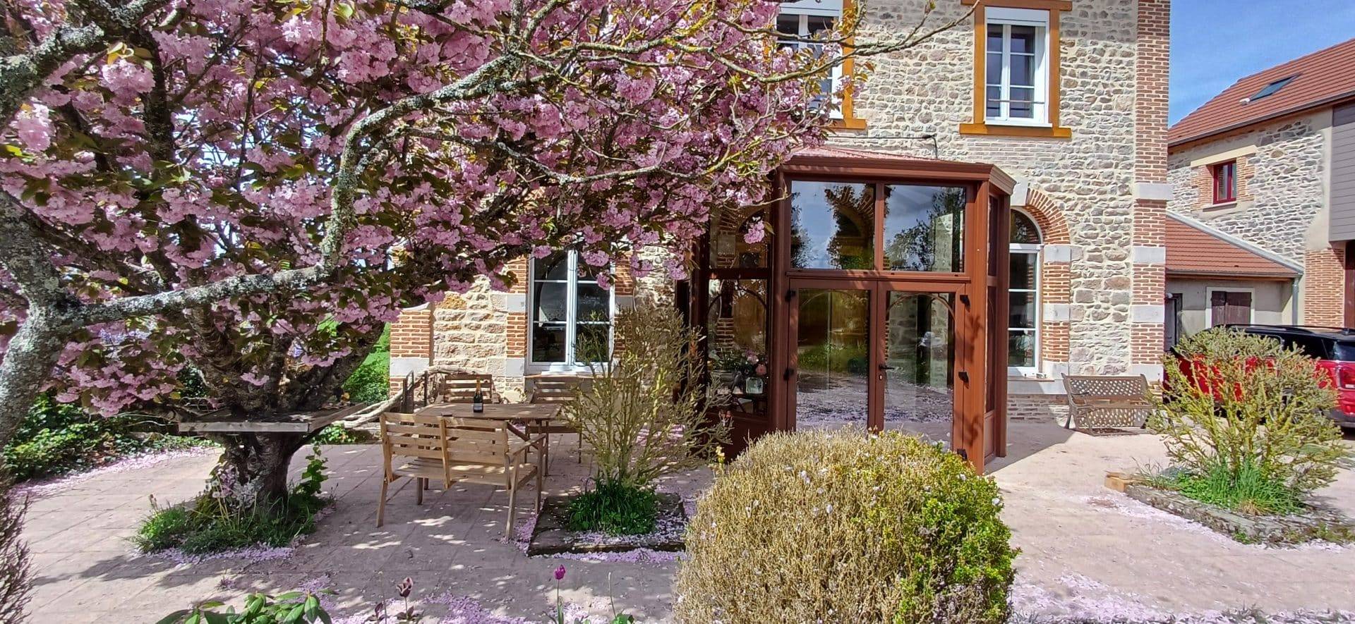 Véranda moderne en verre et bois intégrée à une maison traditionnelle