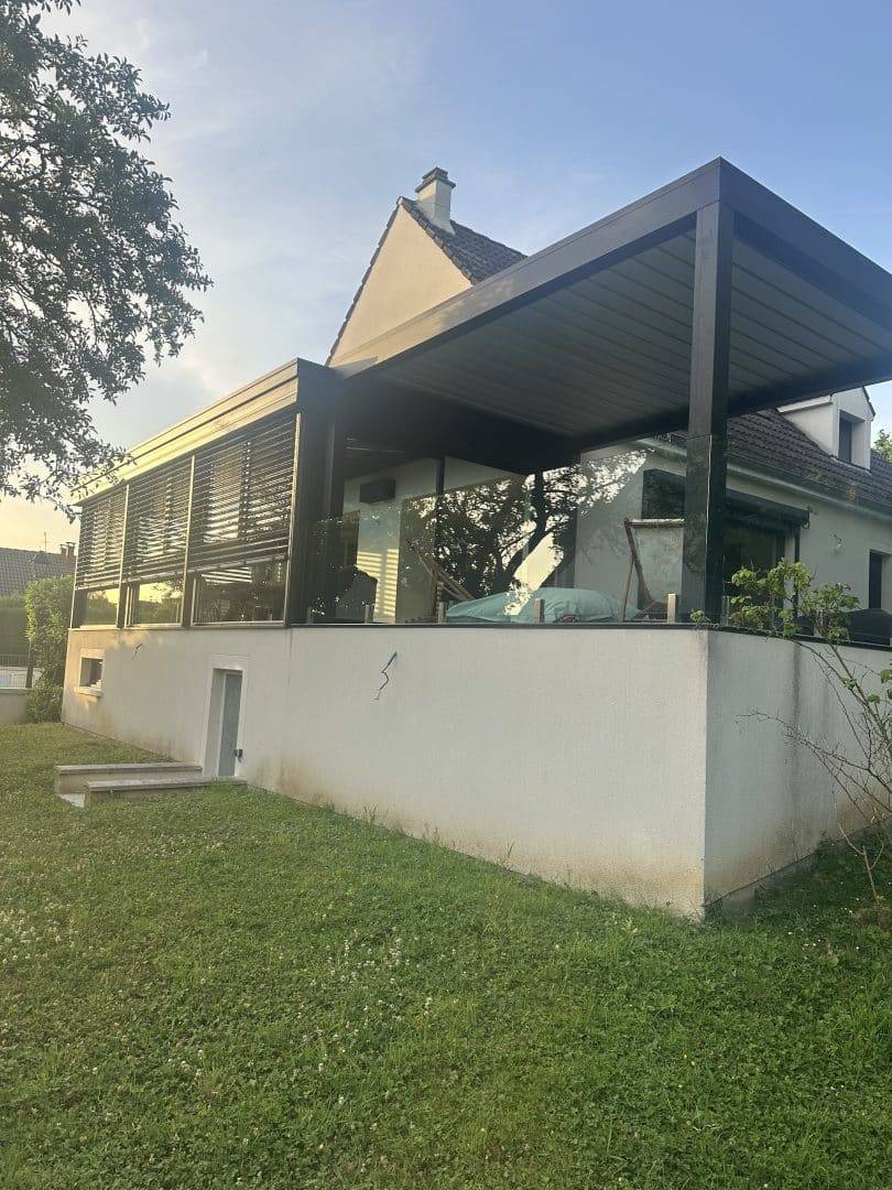 Pergola moderne accolée à une maison avec jardin verdoyant