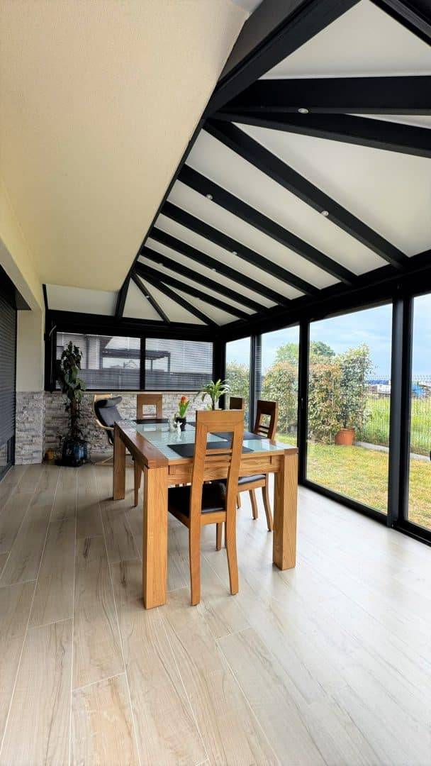 Véranda moderne avec toit en verre et mobilier en bois élégant