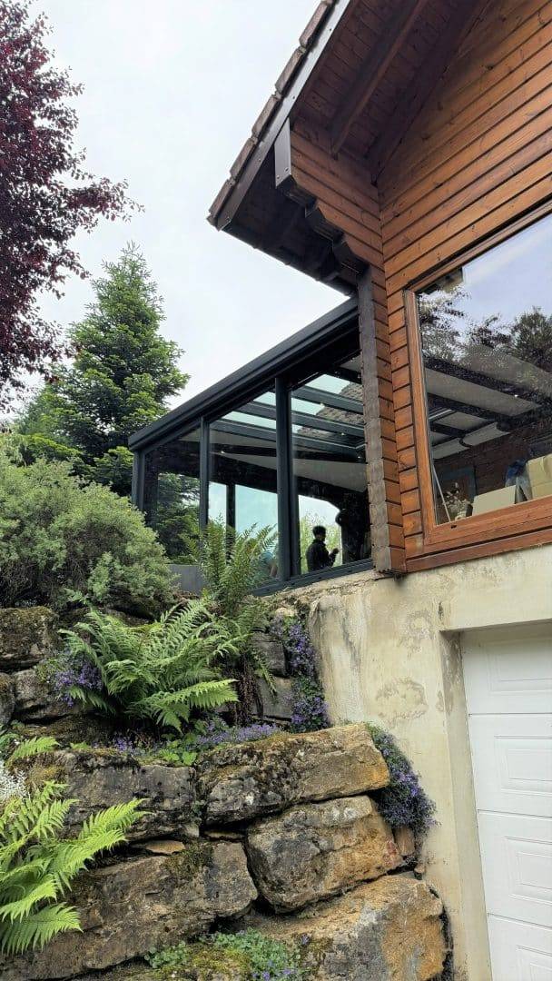 Véranda moderne en verre intégrée à maison en bois rustique