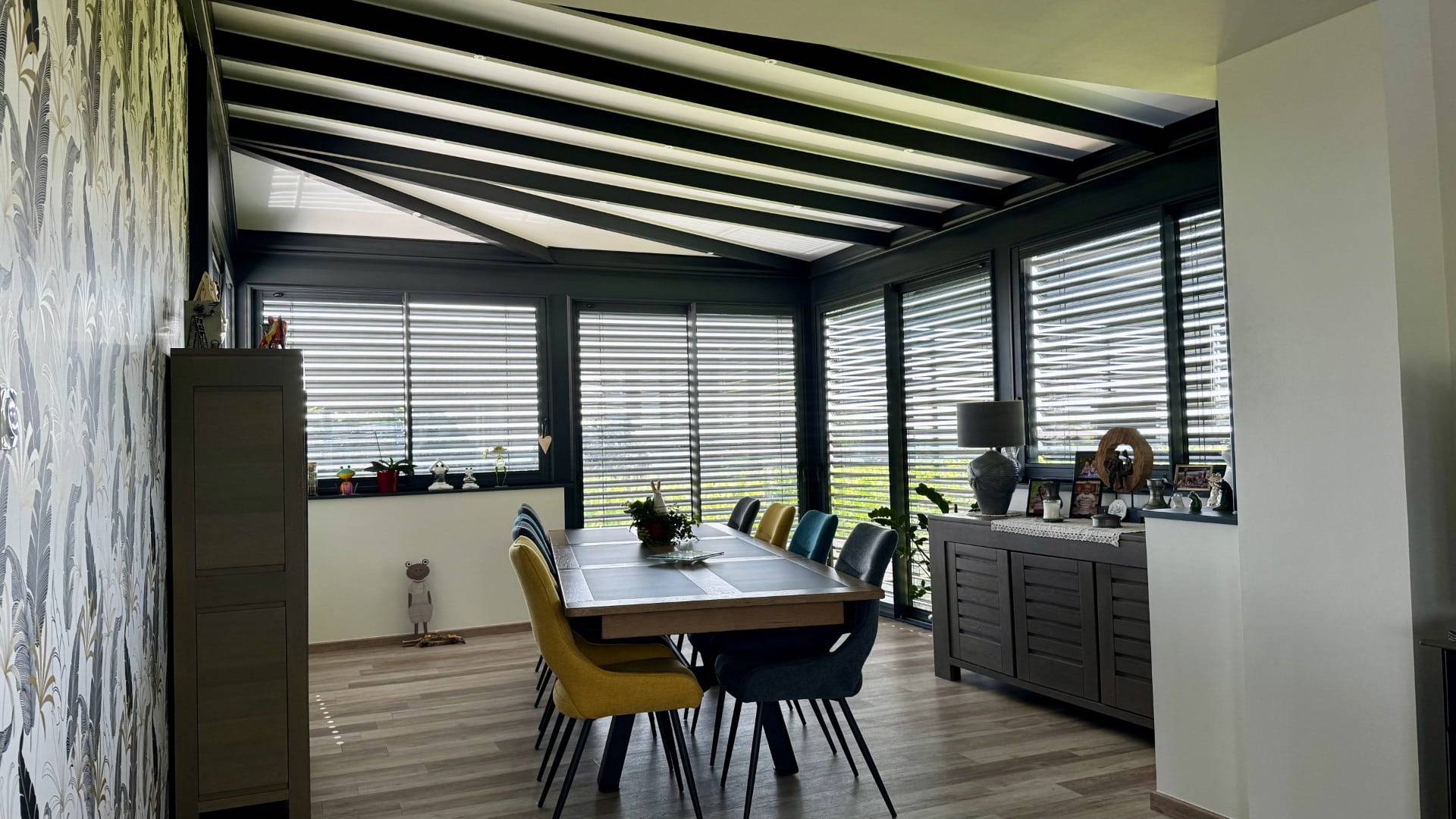 Une véranda moderne avec stores et mobilier contemporain lumineux